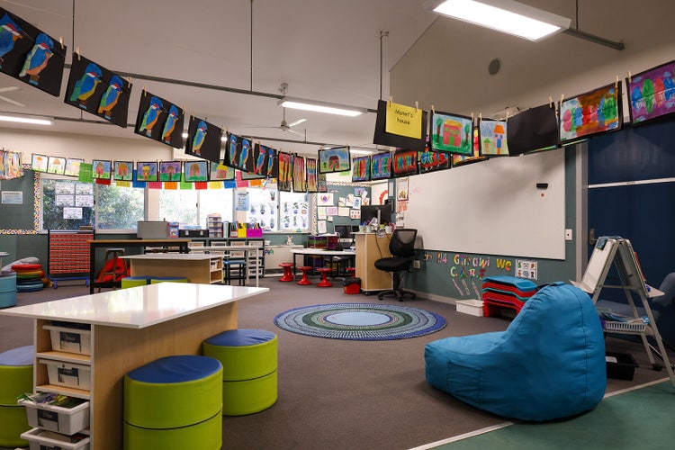 A colourful classroom with art work hangning from ceiling.