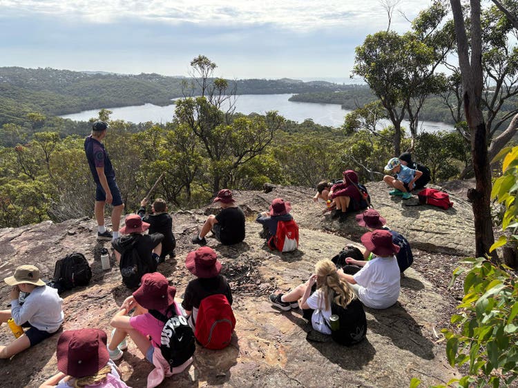 Stage 2 students sitting on a hill overlooking the river at Narabeen camp.